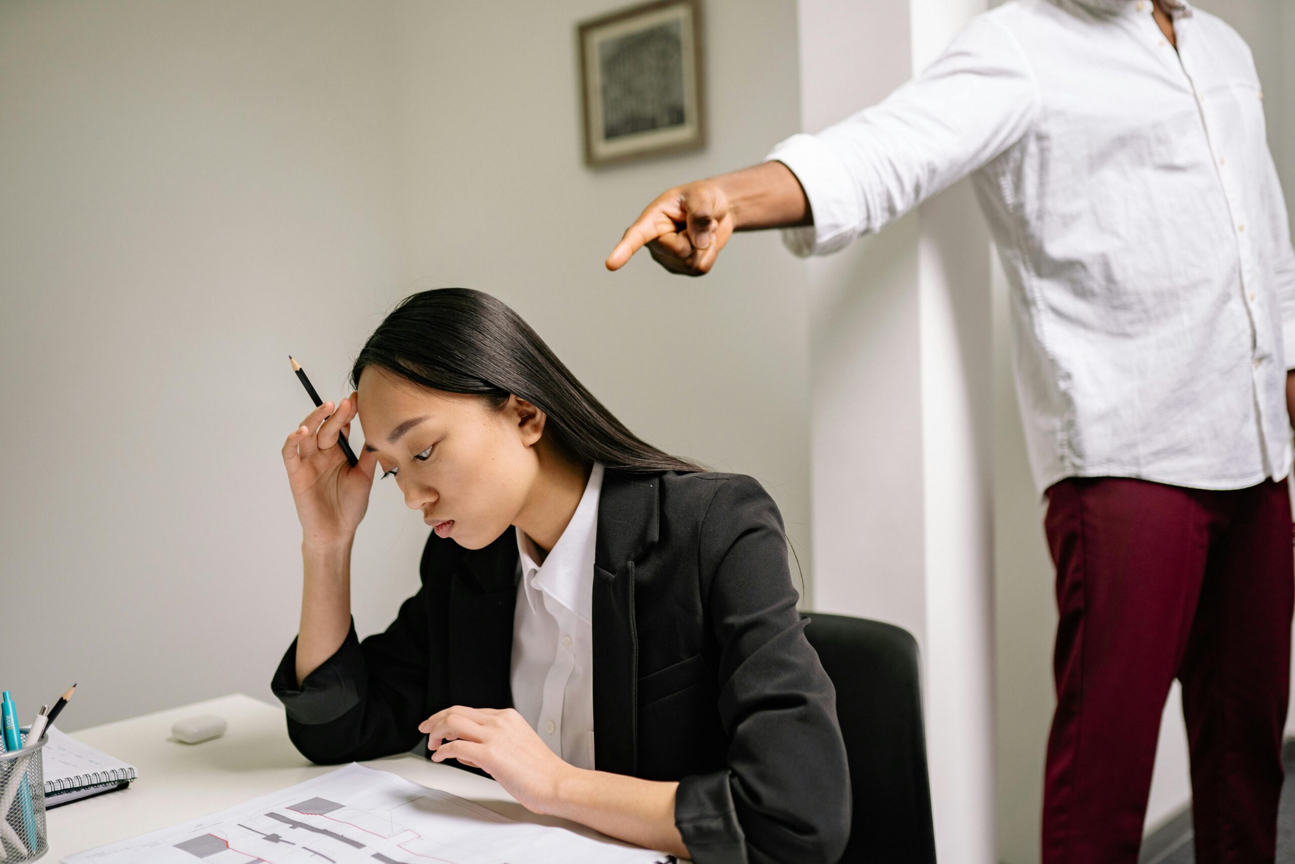 An office scenario depicting a young woman experiencing bullying from a coworker.